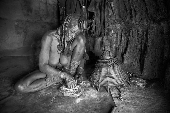 Eine Himbafrau beim parfümieren ihrer Kleidung Eine Himbafrau beim parfümieren ihrer Kleidung