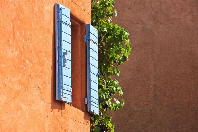 Ockerfarbenes Haus mit blauen Fensterläden in Südfrankreich Ockerfarbenes Haus mit blauen Fensterläden in Südfrankreich