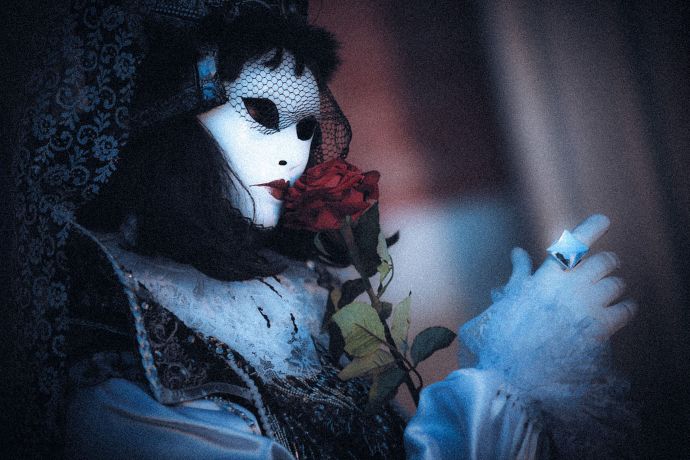 Eine maskierte Frau mit einer Rose beim Karneval in Venedig Eine maskierte Frau mit einer Rose beim Karneval in Venedig